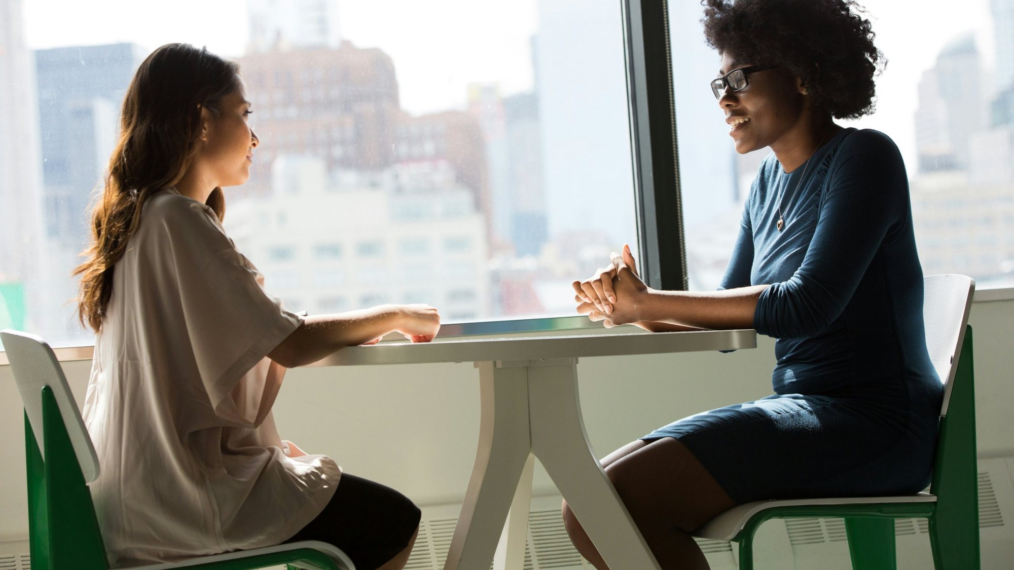Two women talking at a table in an office